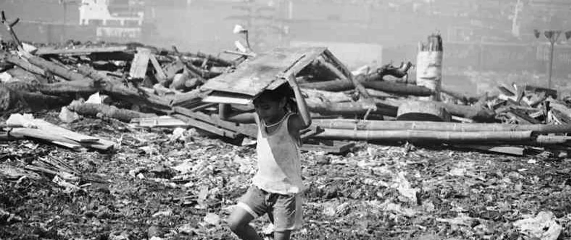 a child carrying a wooden scrap from the dumpsite
