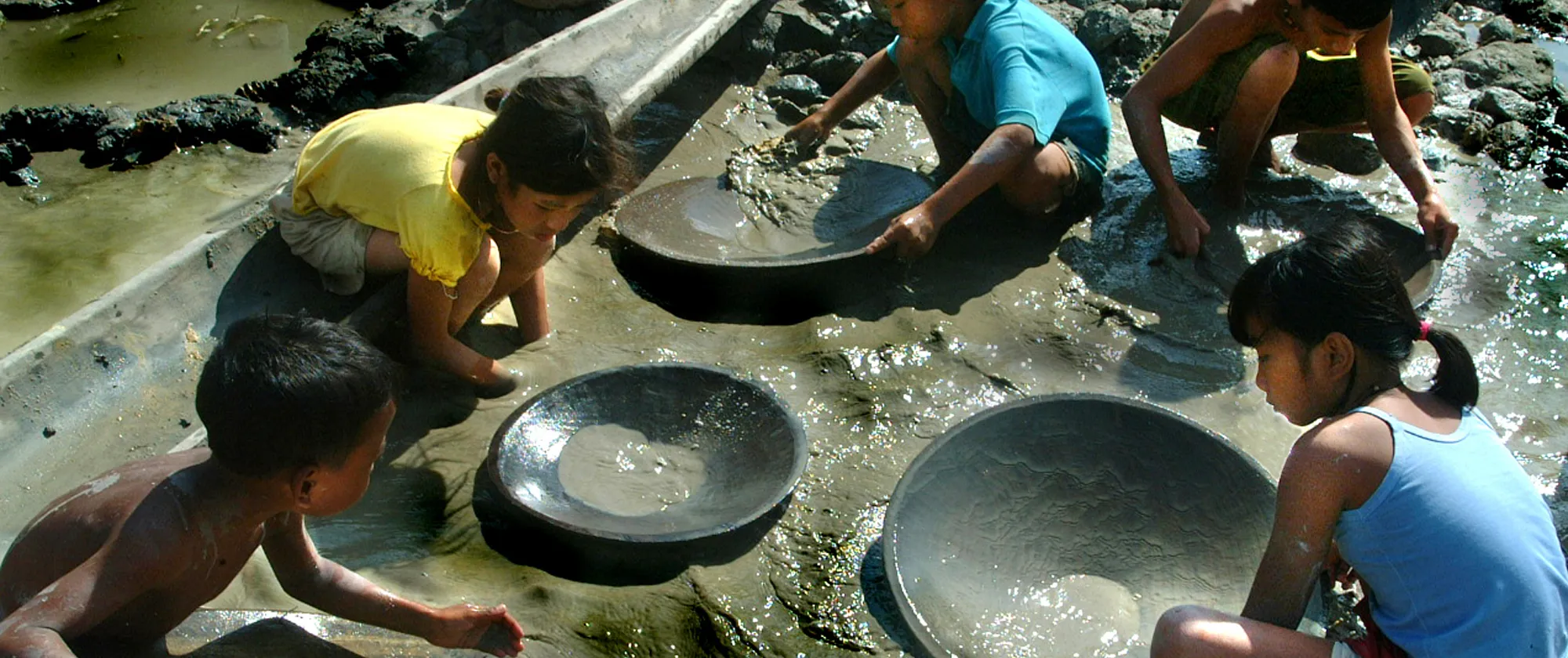 children searching for gold and using heavy metal pans