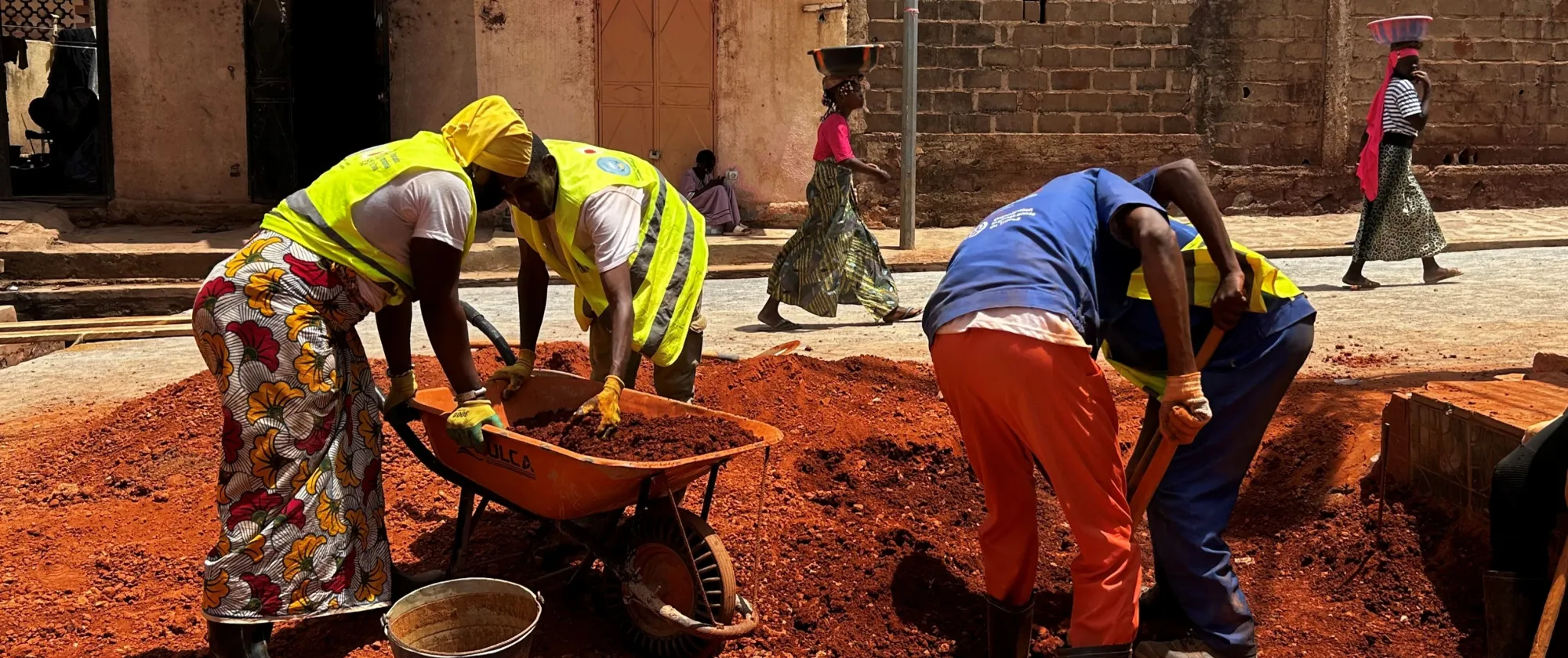 Women and men wearing yellow vests and working to repair road
