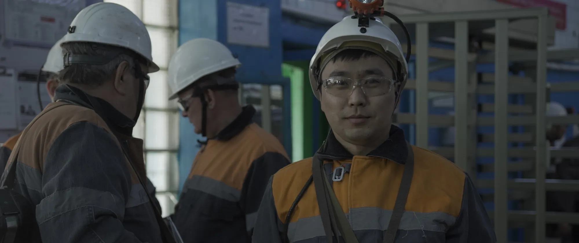 Men wearing helmets and protective equipment inside an industrial facility