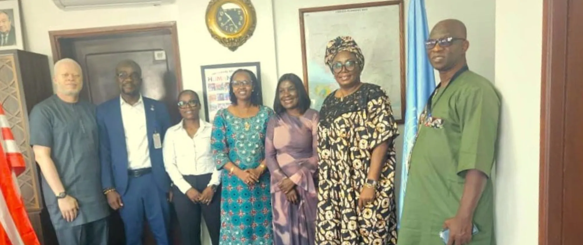 A group of officials pose inside an office near the Liberian and United Nations flags. The participants are gathered following a meeting focused on employment, labour reform, and inclusive development initiatives in Liberia.