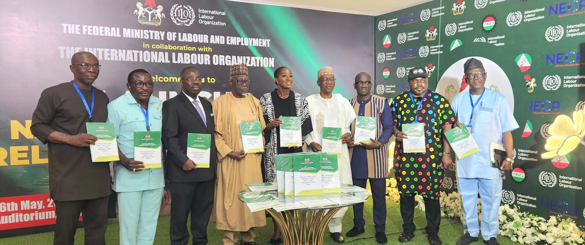 A group photo of government representatives, labour leaders, employers’ organizations, and ILO officials holding copies of the National Industrial Relations Policy at the close of the launch ceremony.