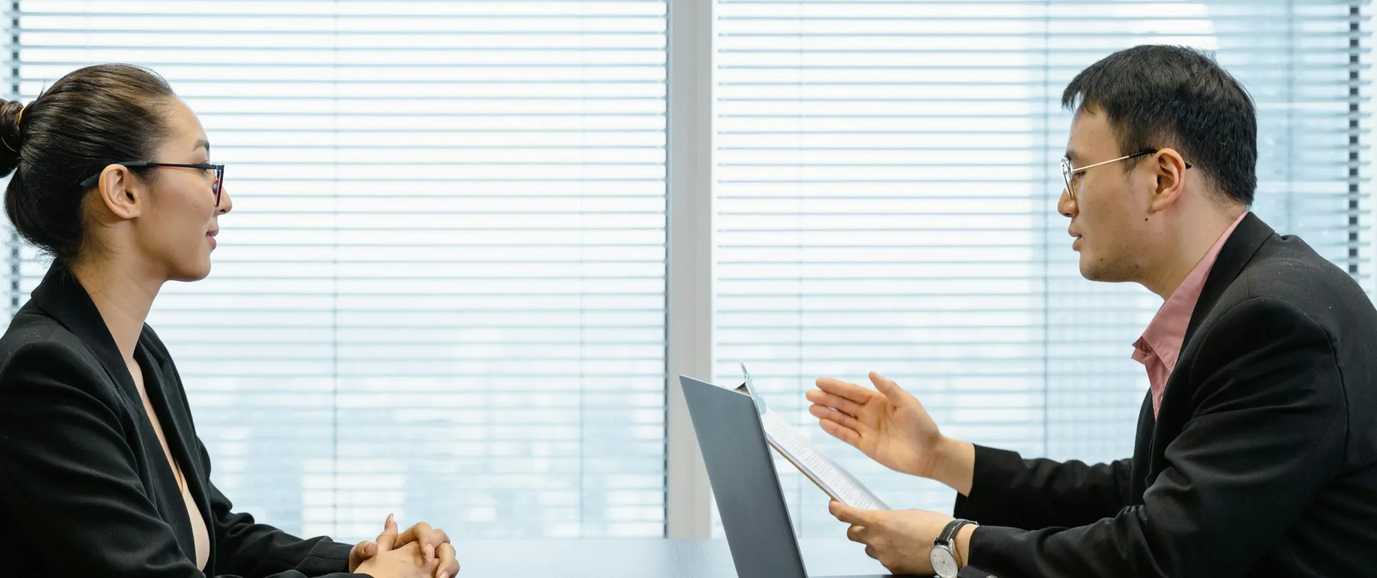 Two businesspeople engaged in a discussion during a professional meeting in an office setting