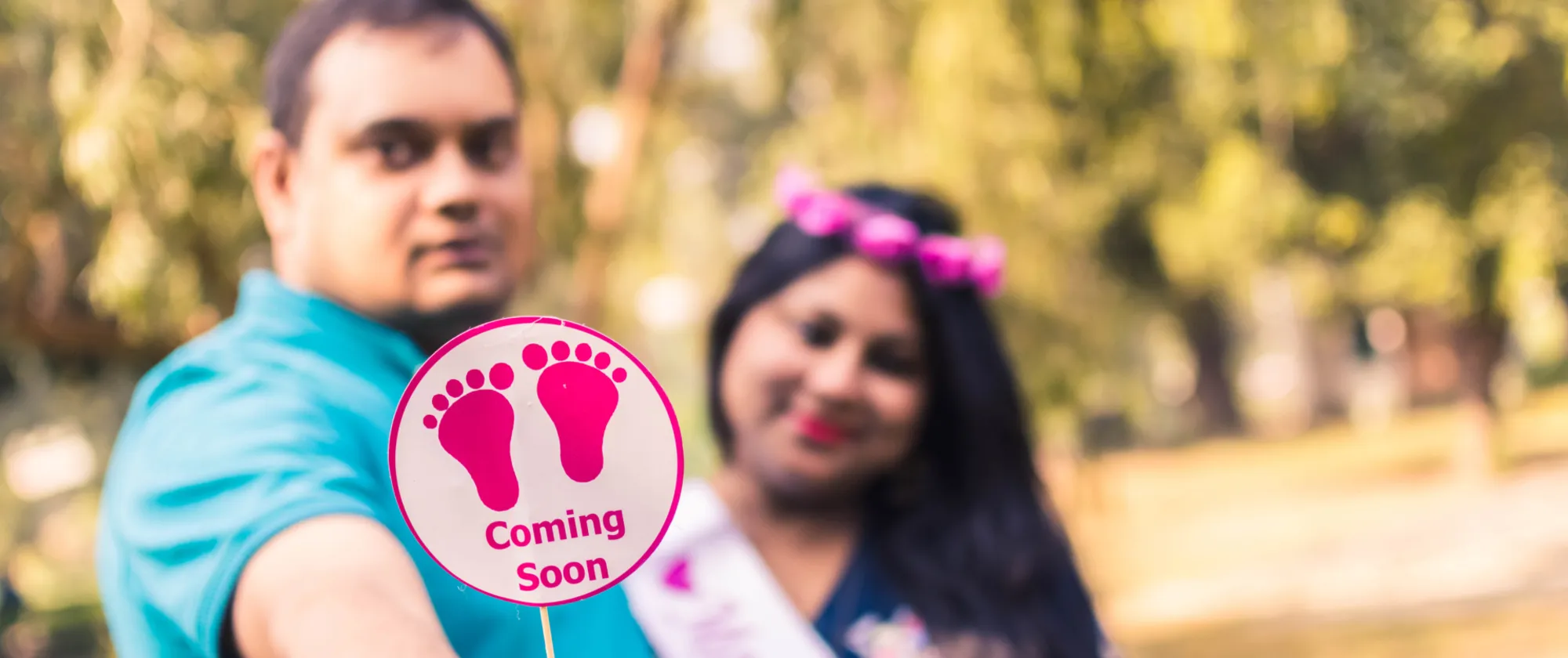 A couple holding a sign reading “Coming Soon”.