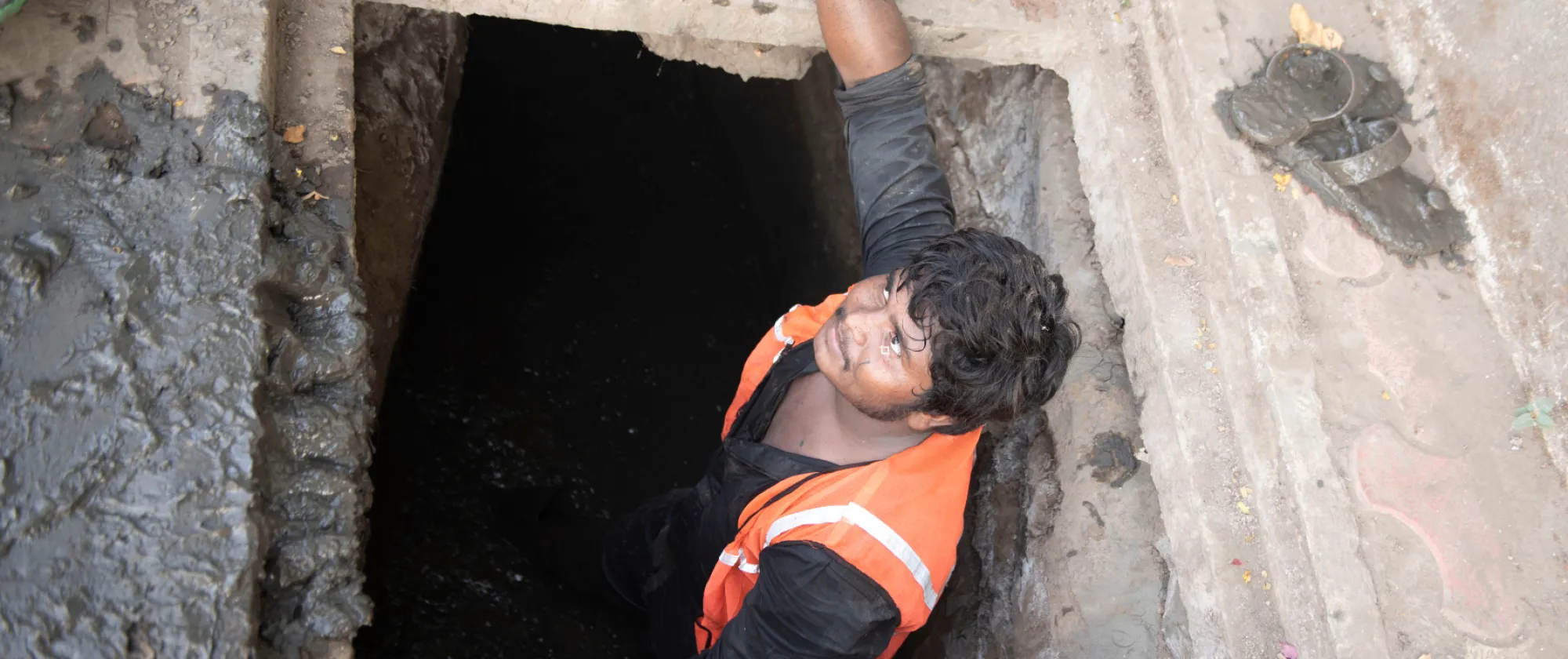 A sanitation worker standing inside a drainage manhole.