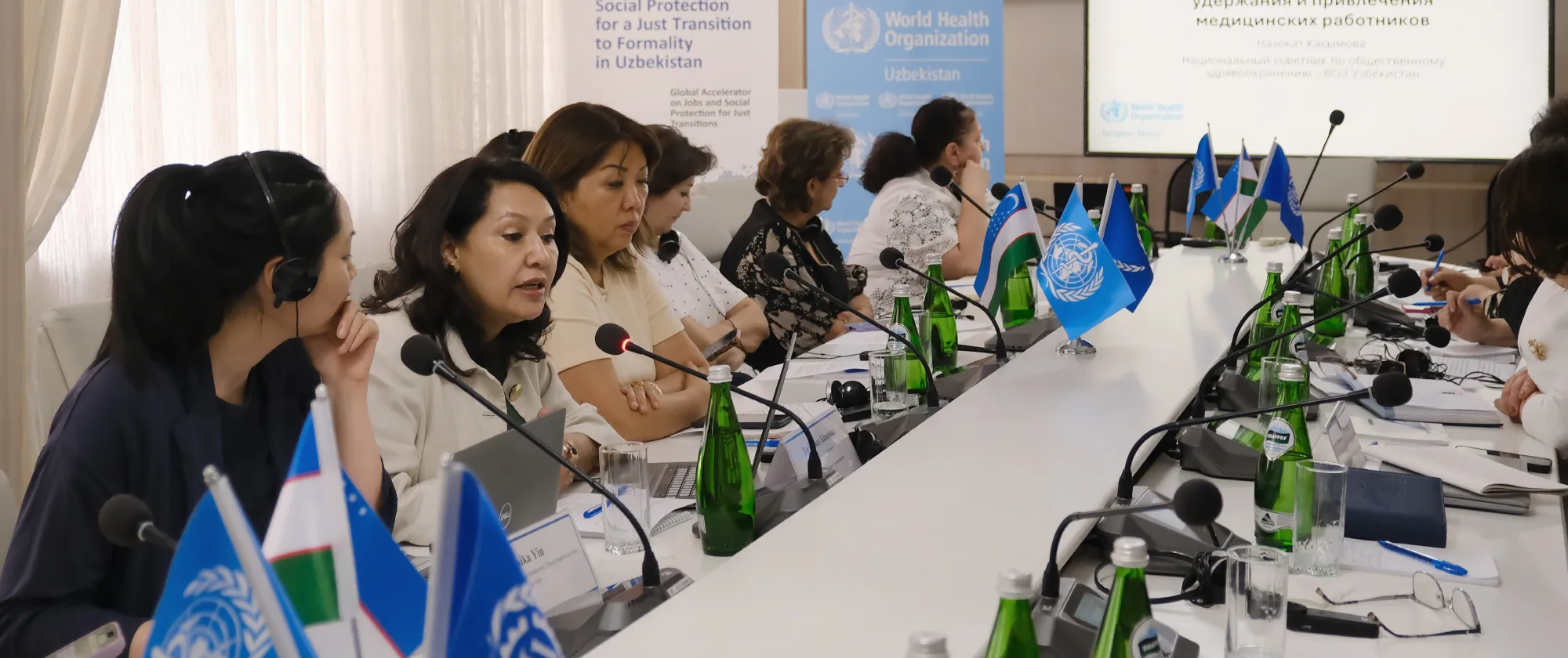 Participants seated around a conference table with a presentation displayed on a screen