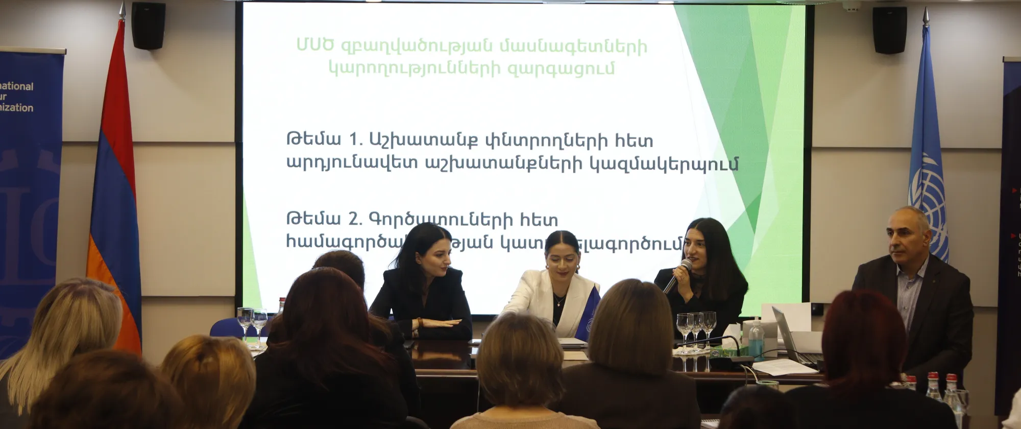 Panellists seated at a table, with an audience facing them.