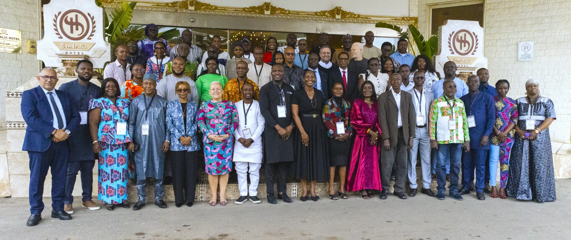 Large group photo of participants standing outside a hotel venue after a workshop or conference.