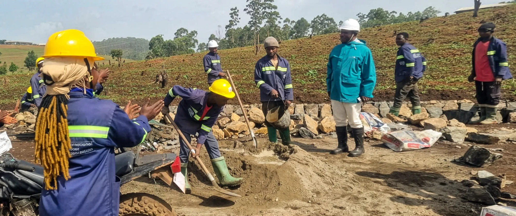Workers in safety gear rehabilitate a road in Nkambe as the town mayor observes the worksite.