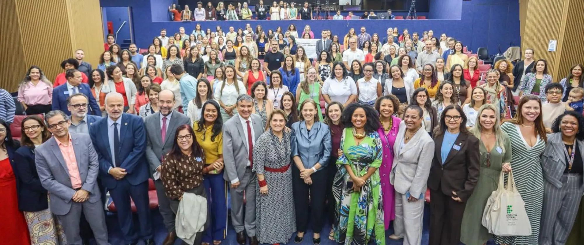 Grupo de pessoas que participou do evento posa para a foto com o auditório ao fundo.