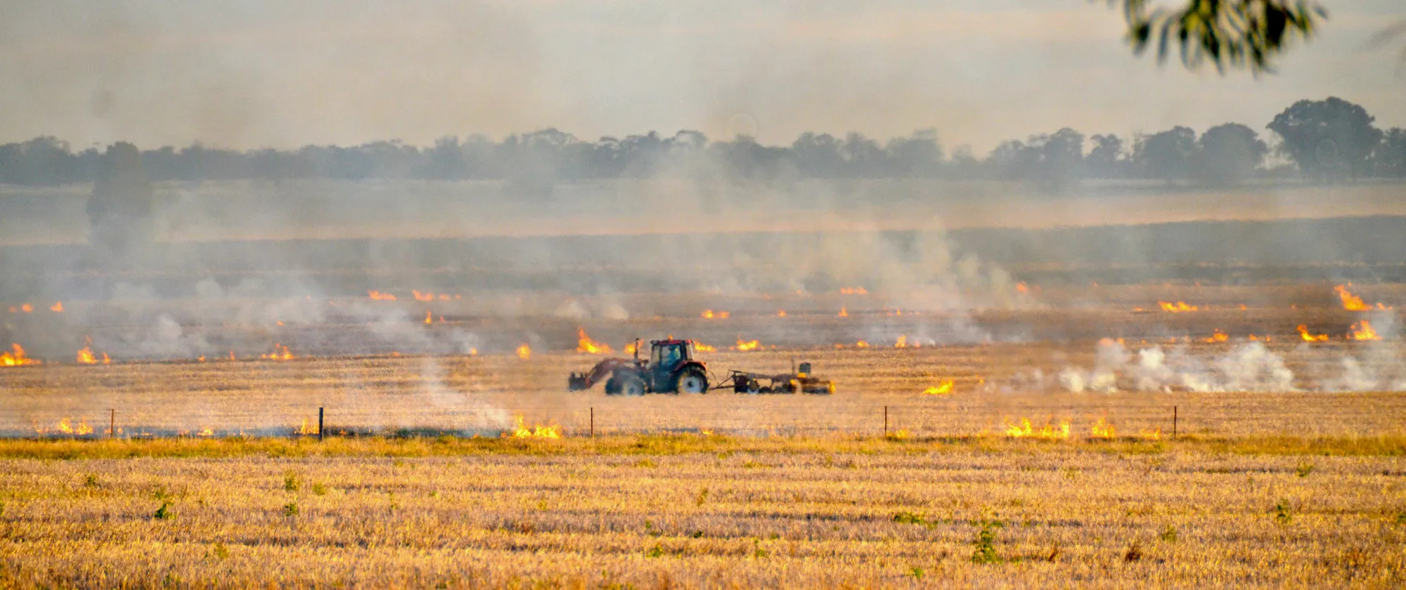 Farming truck in a field with fire