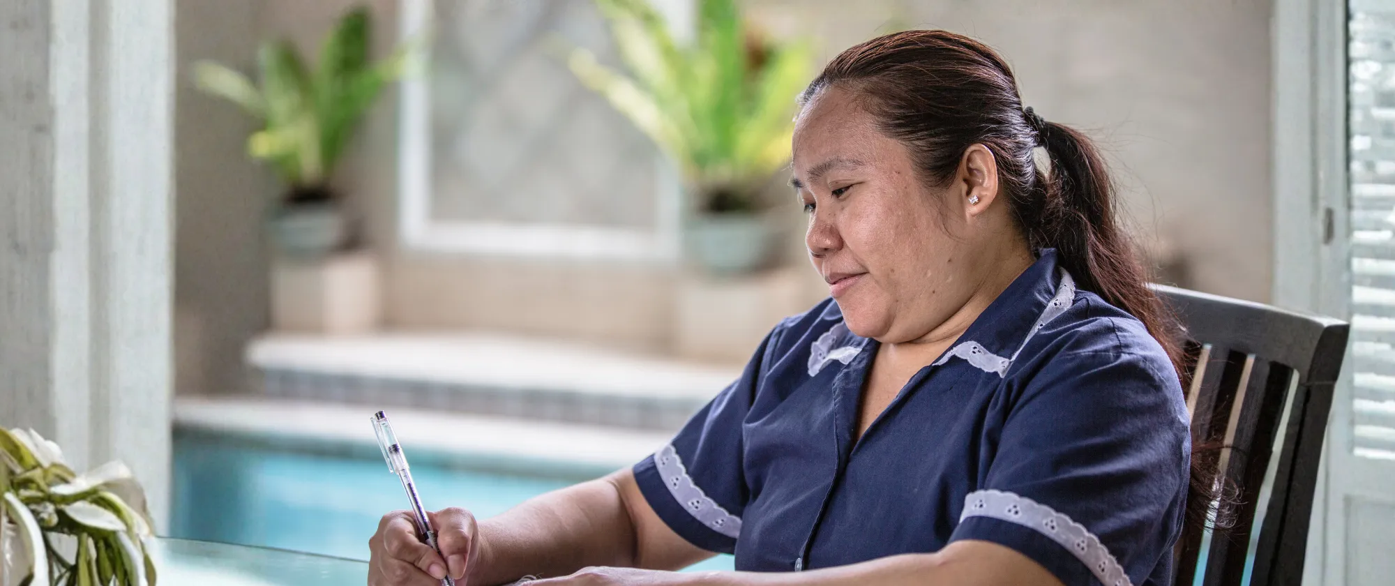 Luna Rose Escosa, a domestic worker, sits while writing her daily tasks.