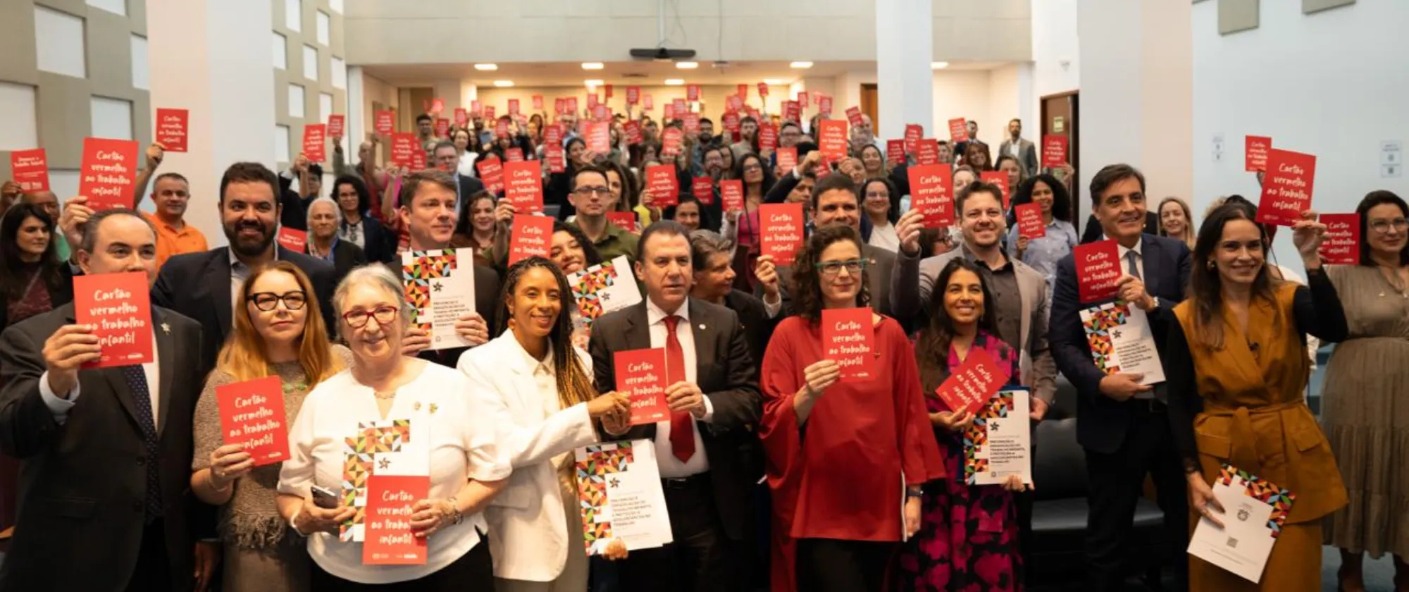 Autoridades e público segura o cartão vermelho contra o trabalho infantil no evento de lançamento do IV Plano Nacional 
