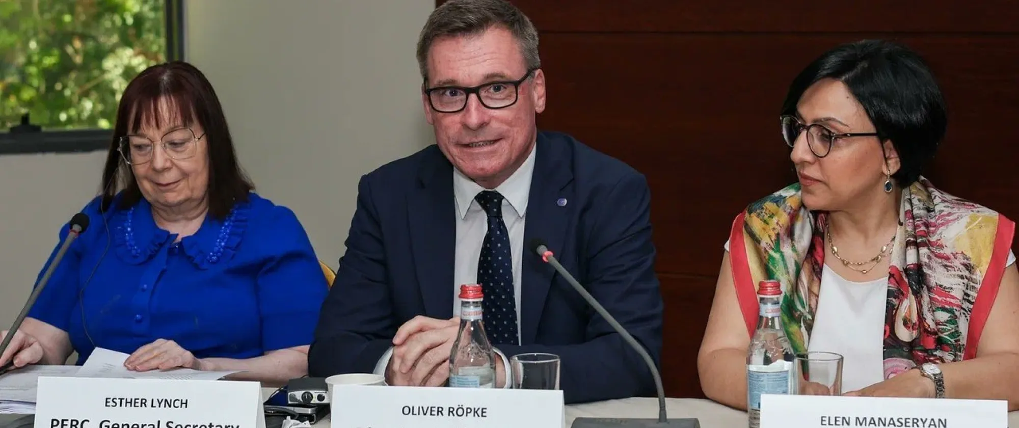 Three people sitting at a table with mics in front of them