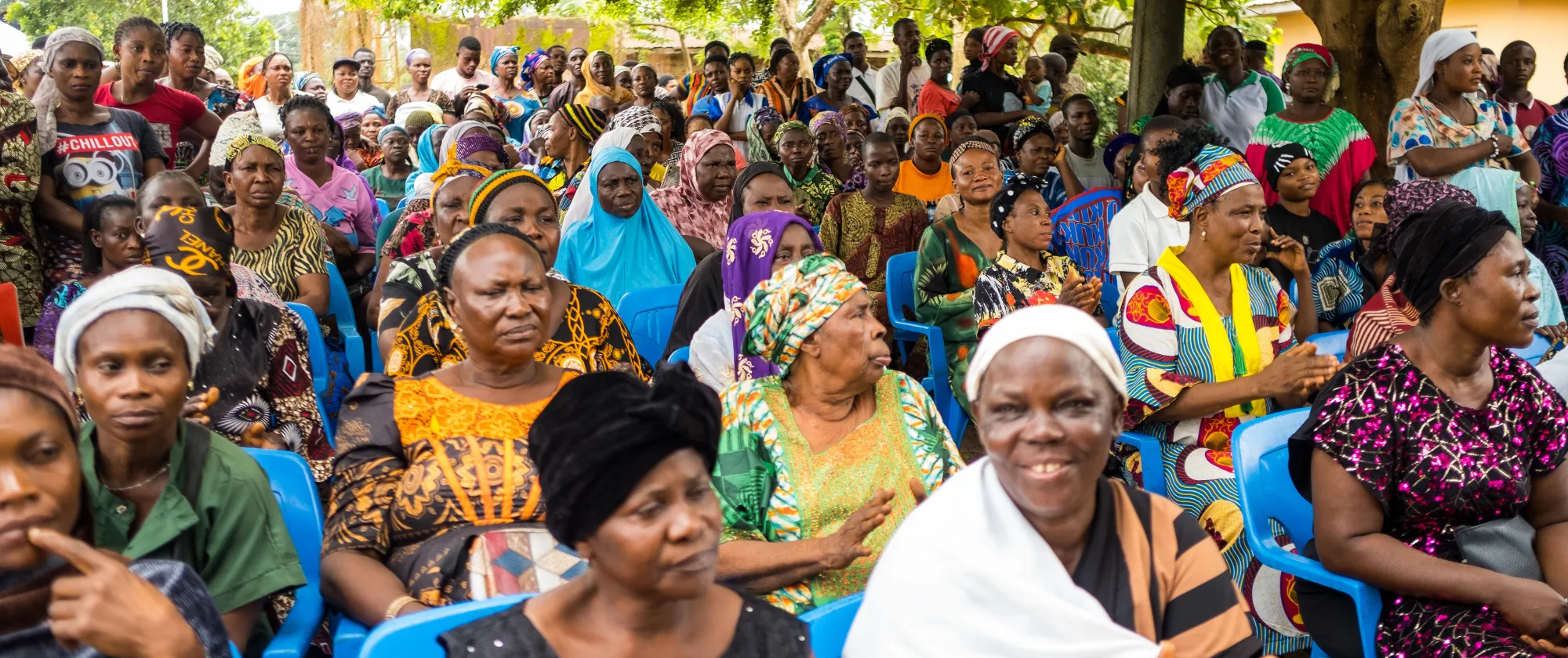 A large group of women, men and young people participate in a community sensitization session focused on health insurance, social protection and child labour prevention.