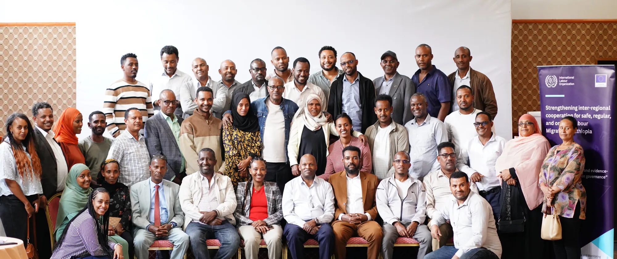 Group photo of workshop participants standing and seated beside an ILO and European Union project banner.