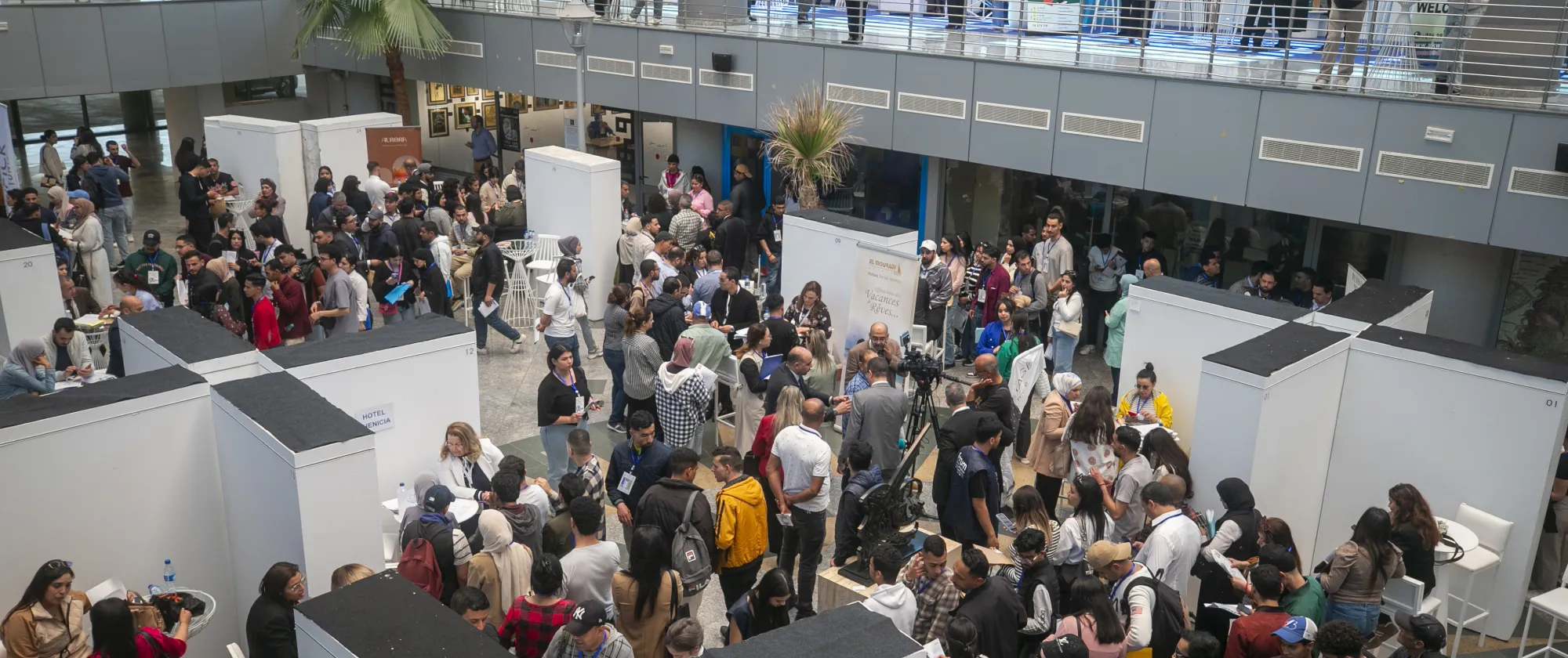 Vue d’ensemble de l’espace d’exposition du Forum tuniso-européen de l’Hôtellerie & de la Restauration. De nombreux jeunes circulent entre les stands, échangent avec les exposants et consultent les opportunités proposées par les établissements de formation, les employeurs et les institutions participantes.