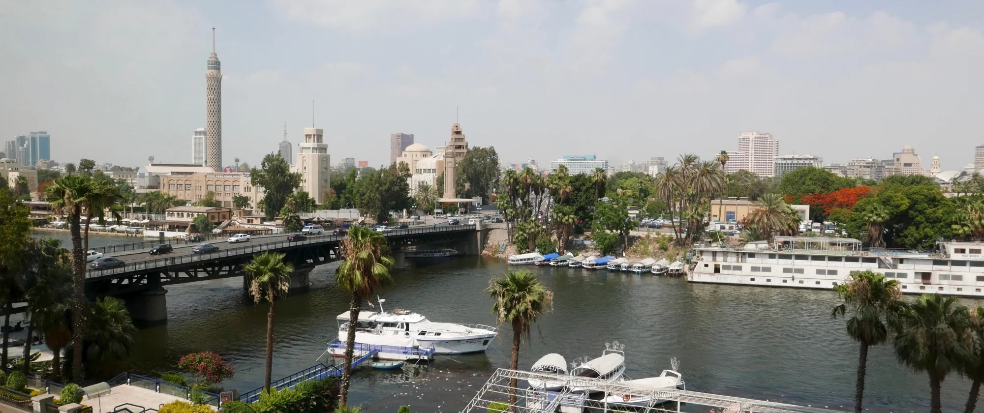 A birds-eye view of Egypt's Nile River showing a cruise boat in the water and restaurants and hotels.
