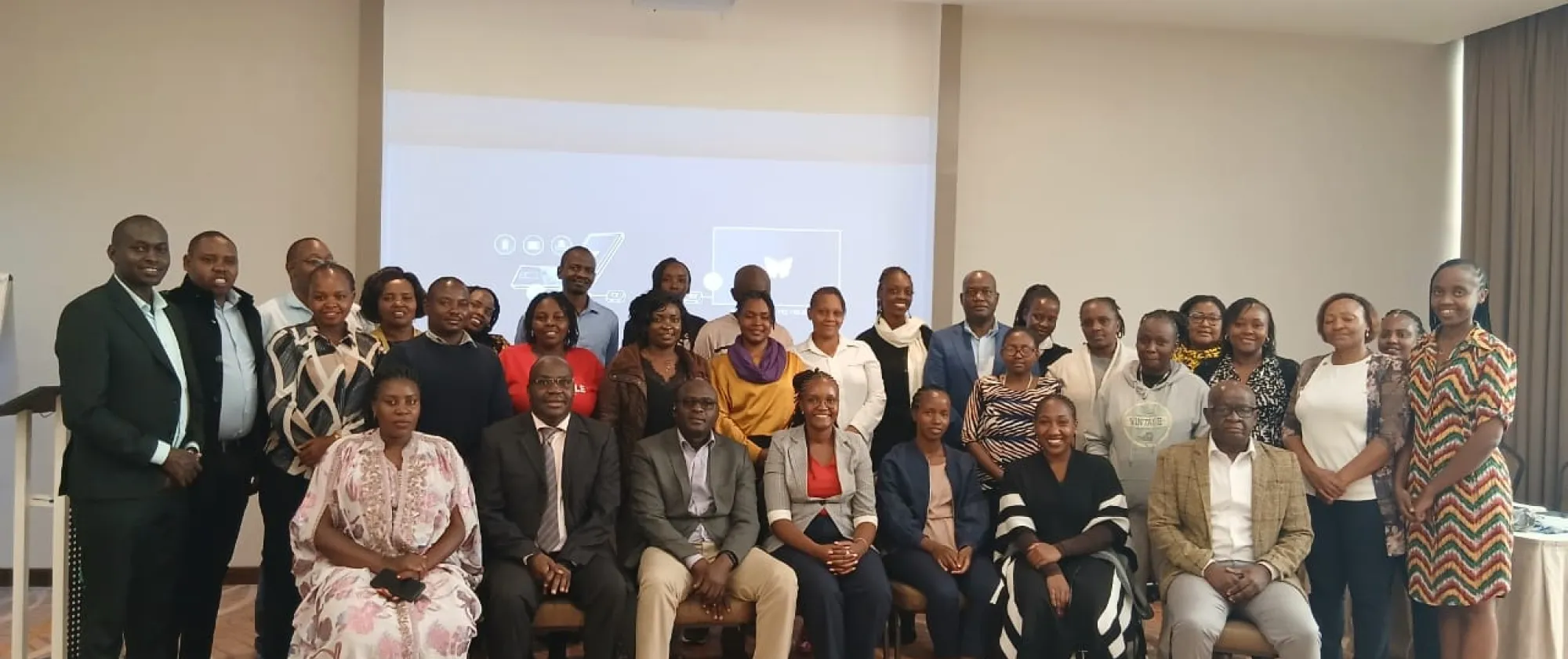 Group photo of participants standing and seated during a workshop or validation meeting in a conference room