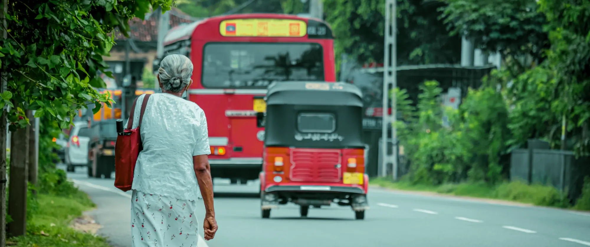 Elderly woman walking on city road in Sri Lanka