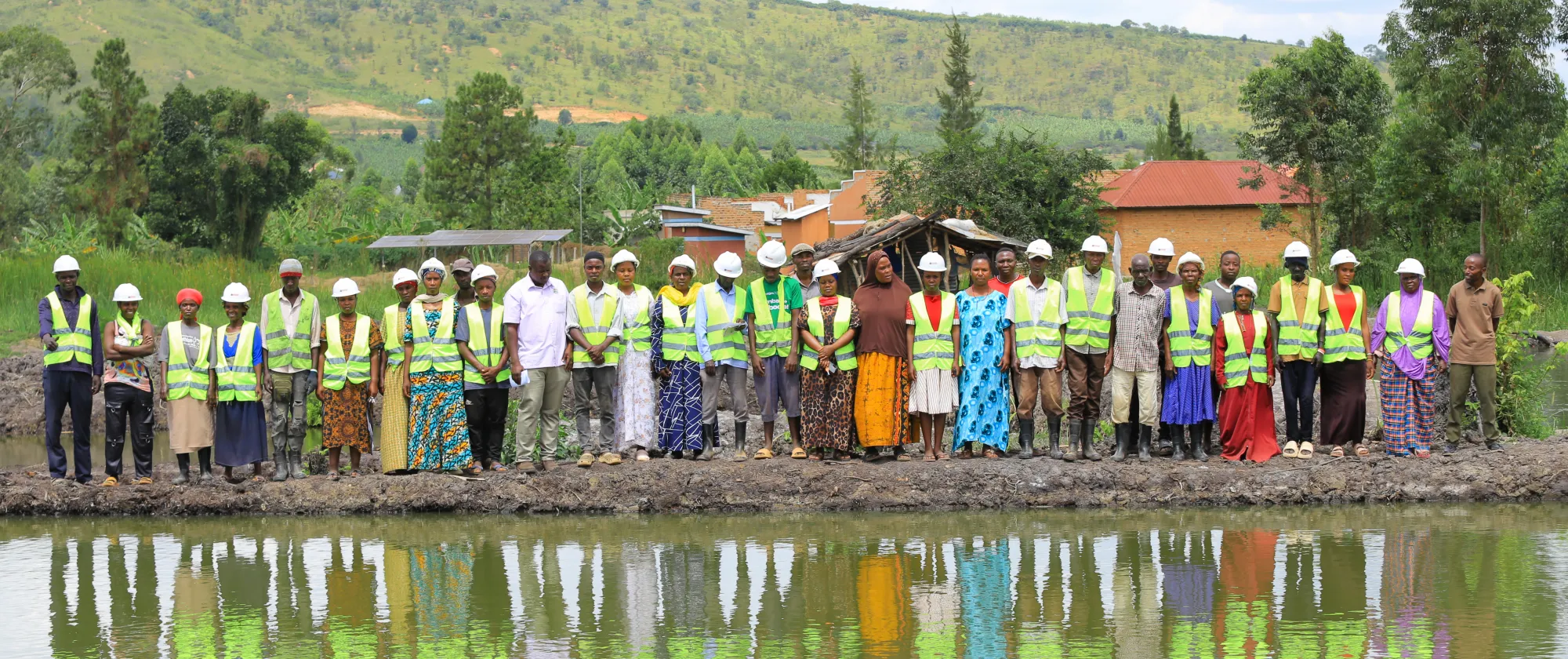 labour based fish farming trainee workers standing across the fish pond