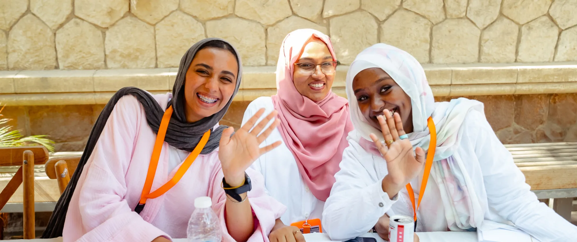 Three women seated at a table laugh to the camera.