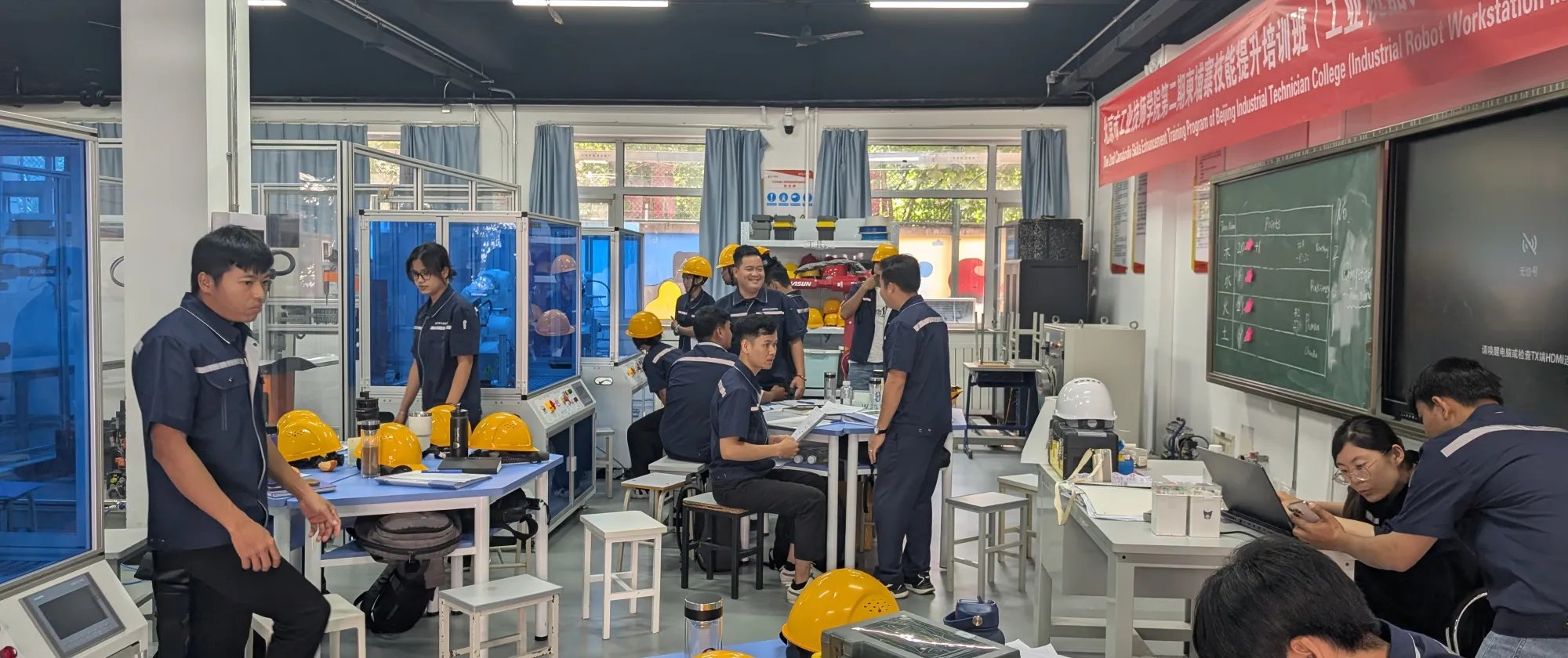Participants  gather around equipment in a workshop equipped with industrial machinery and workstations. 