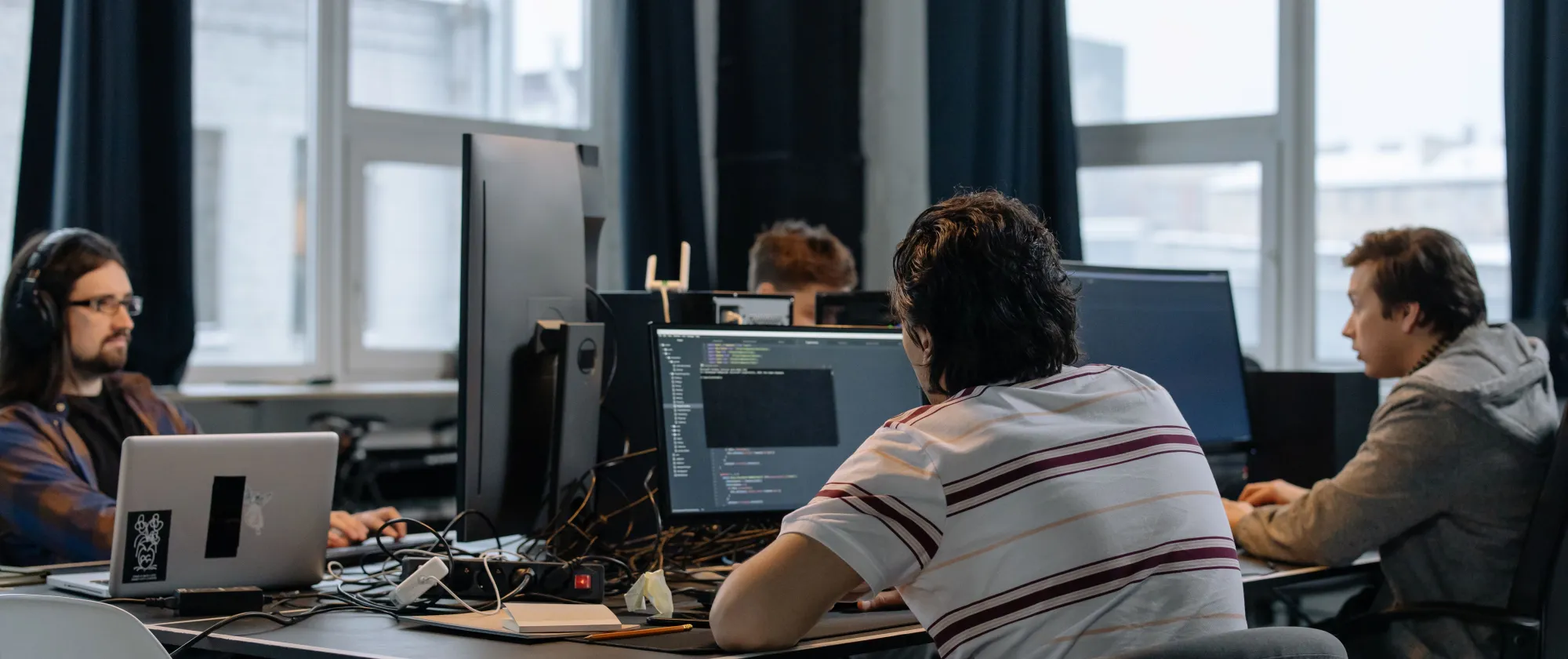 Team of developers working together on computers in a modern tech office.