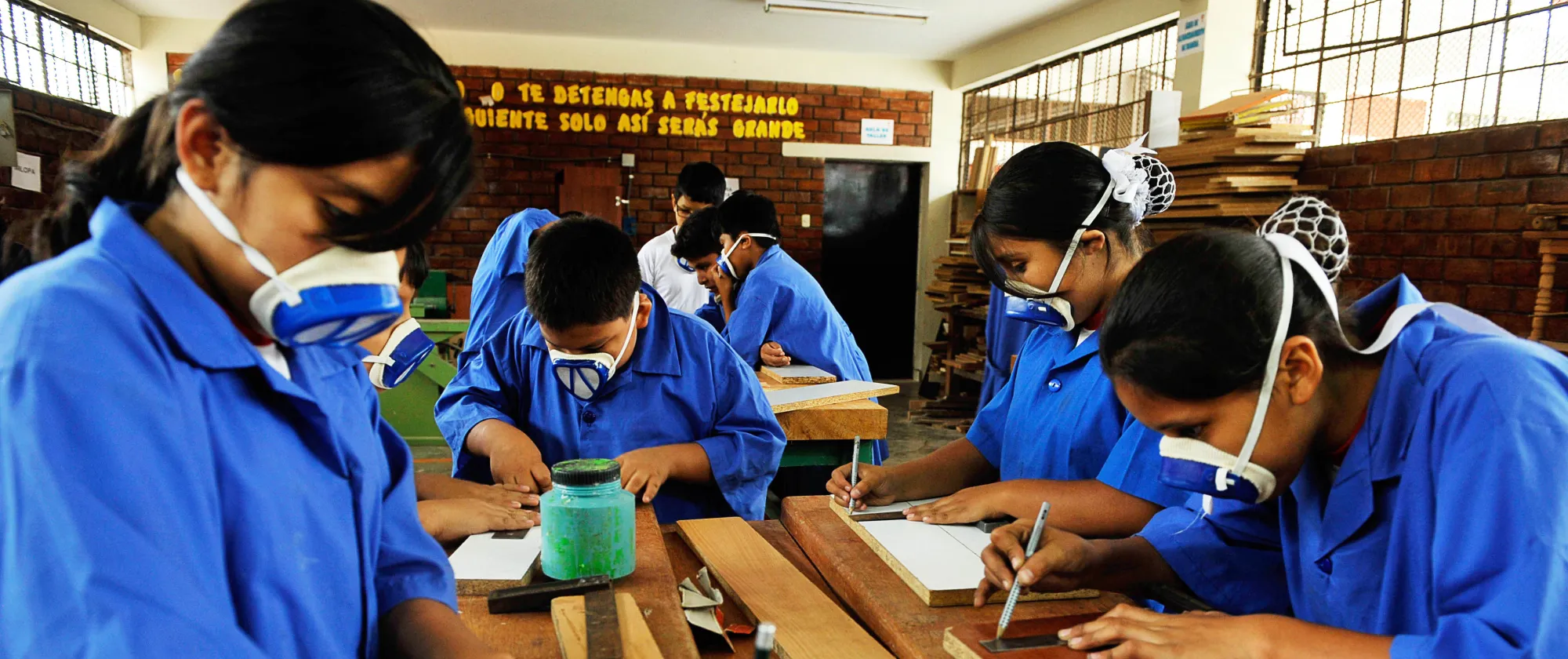 Students wearing protective masks measure and work on wooden boards during a woodwork class at the Fe y Alegría school in Lima, Peru.