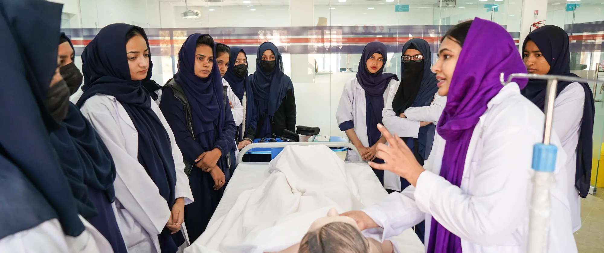 Zahra demonstrates a clinical procedure to nursing students during a practical training session.