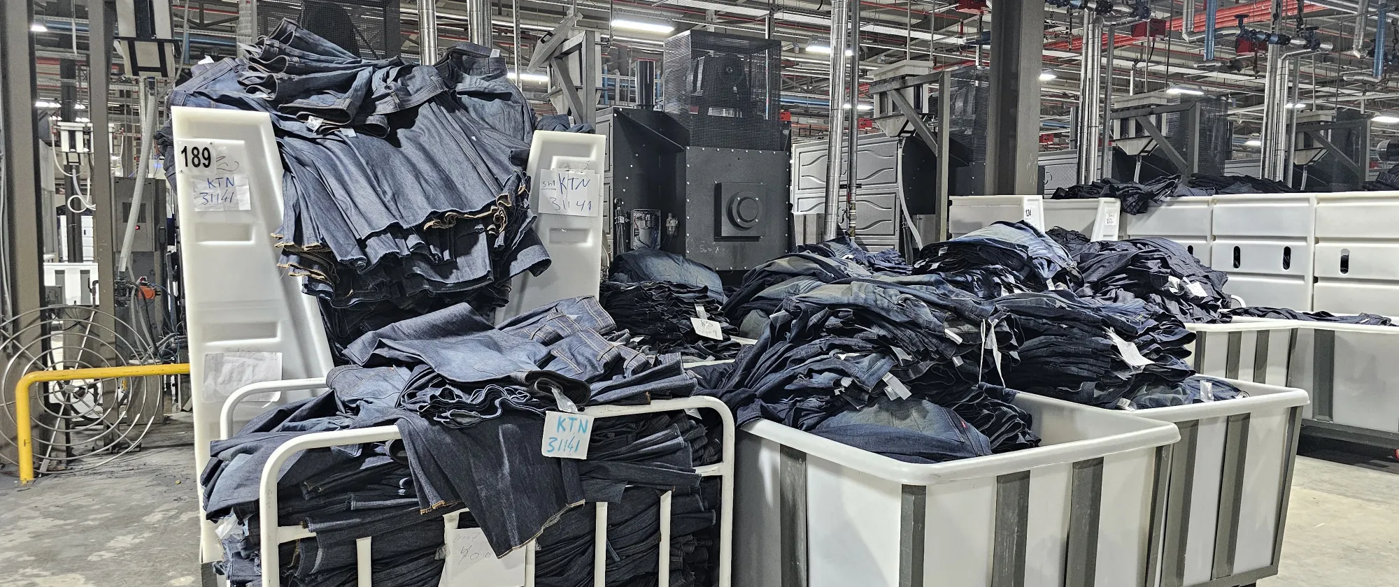 Stacks of denim garments in production carts at Eroğlu Manufacturing Studio in Ismailia, Egypt.