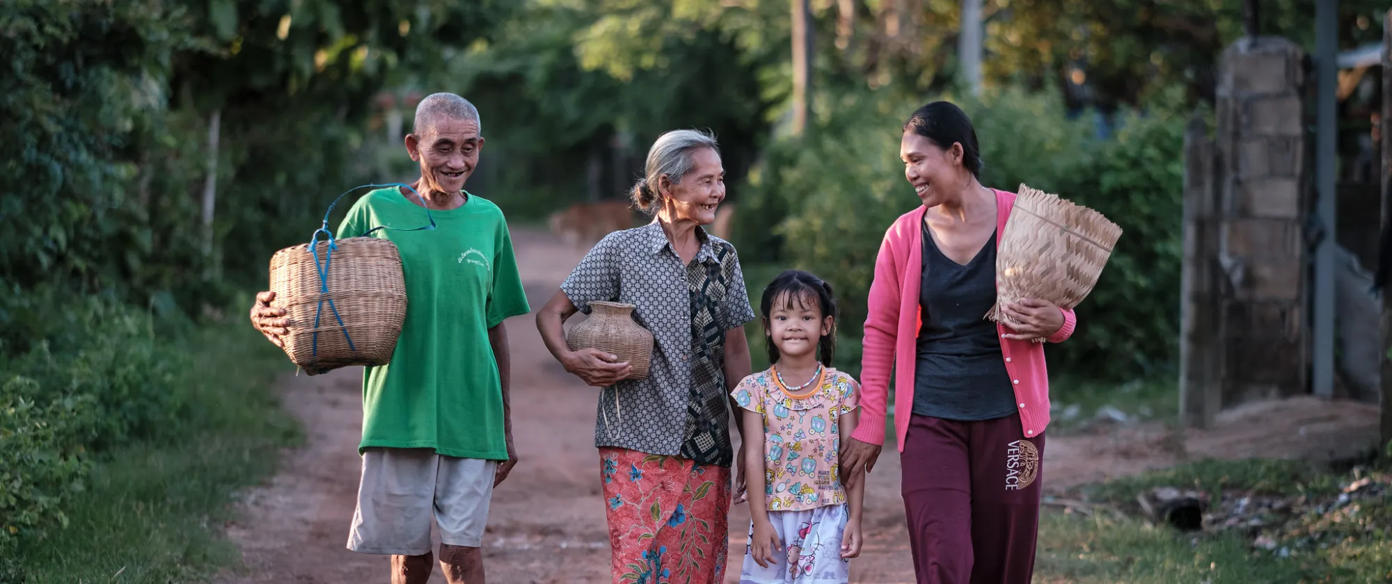 Three generations of a family walk together along a rural road.