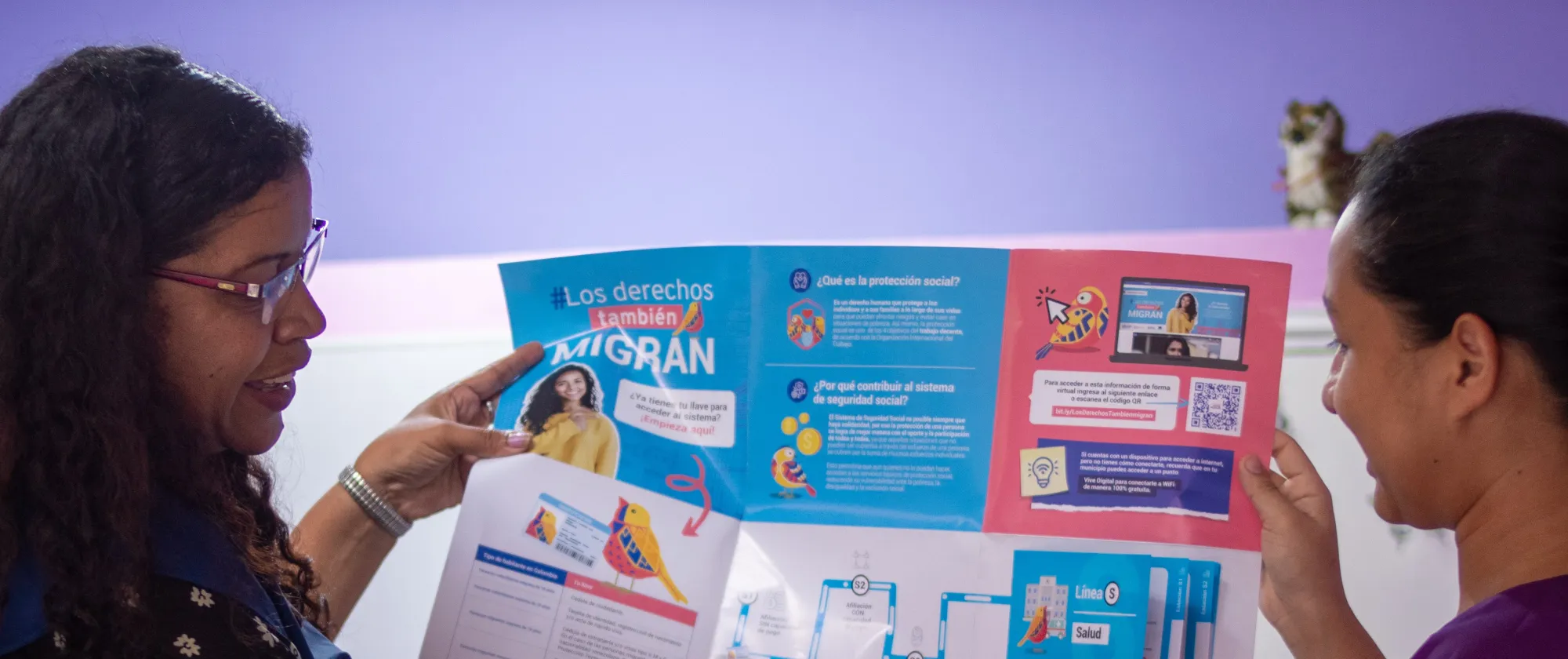 Ditraiza Ramírez is a Venezuelan migrant entrepreneur on the left hand side of the picture looking at a leaflet on the migrants' rights