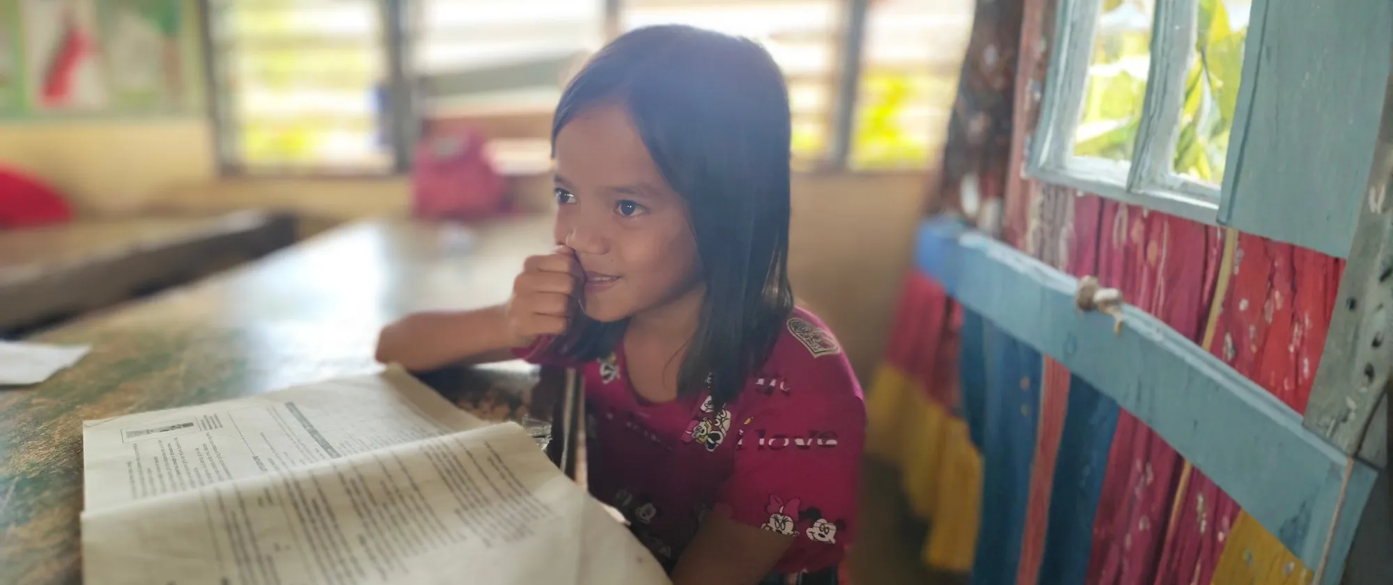 An elementary school girl smiling and reading her book.