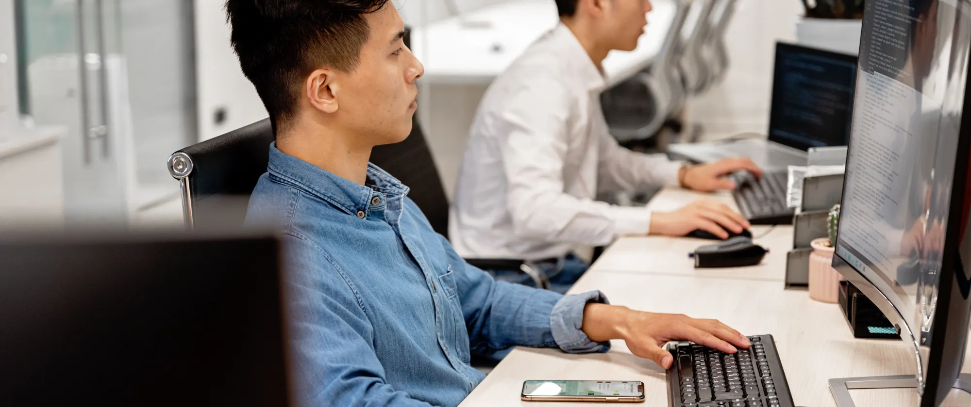 Young professionals working on computers in a modern office environment, focused on their tasks.