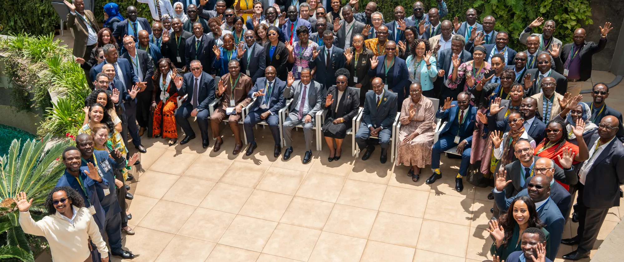 Large group of participants posing and waving during a regional meeting.
