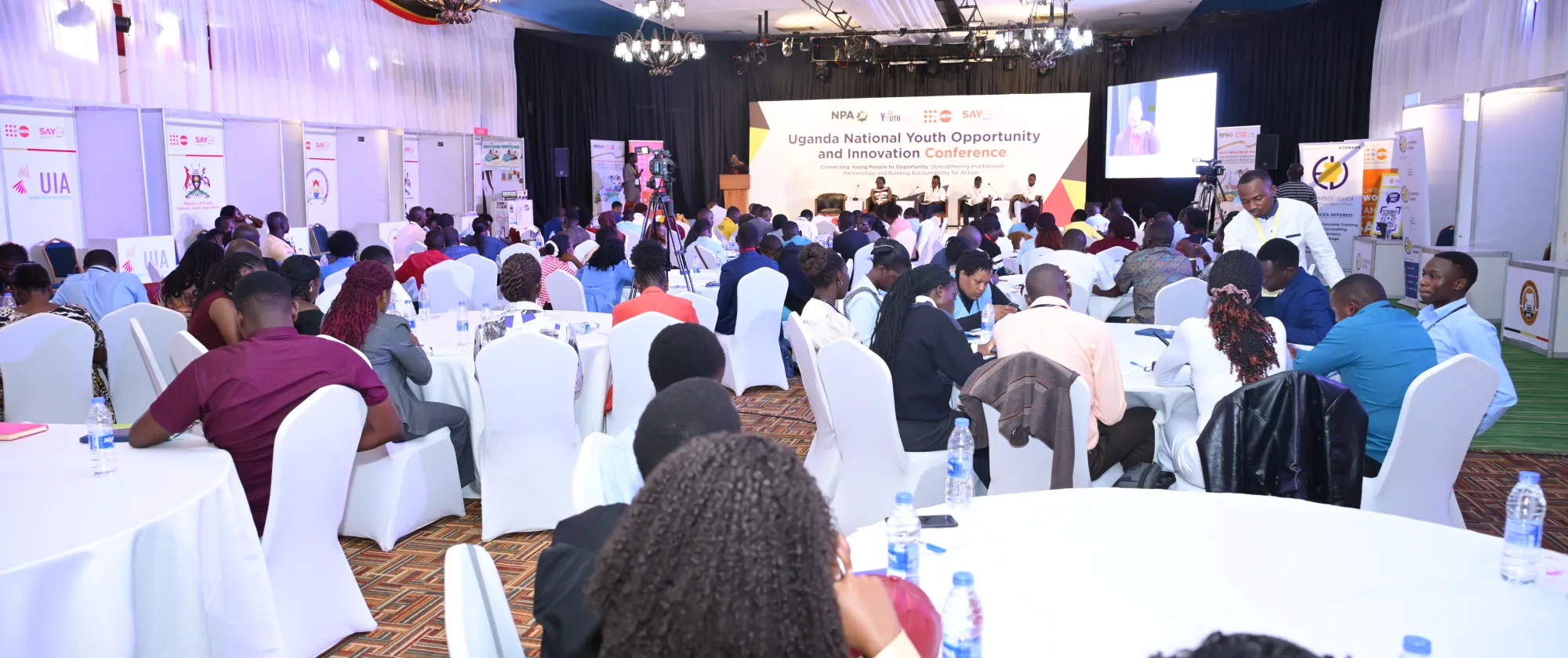 participants sitting at round tables at an event in Uganda