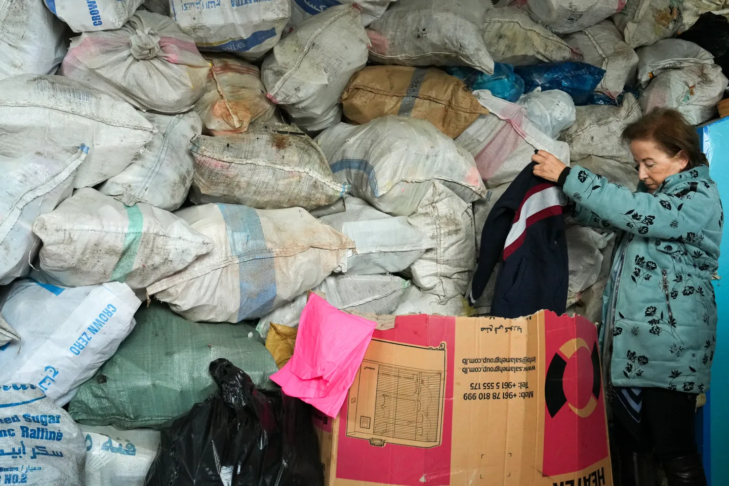woman sorting old clothes at recycling unit