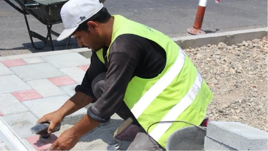 A worker laying tiles on a pavement in Lebanon