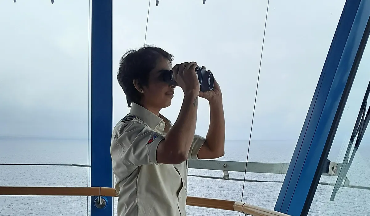 Nayomi Amarasinghe, a woman seafarer looking through binoculars on a boat
