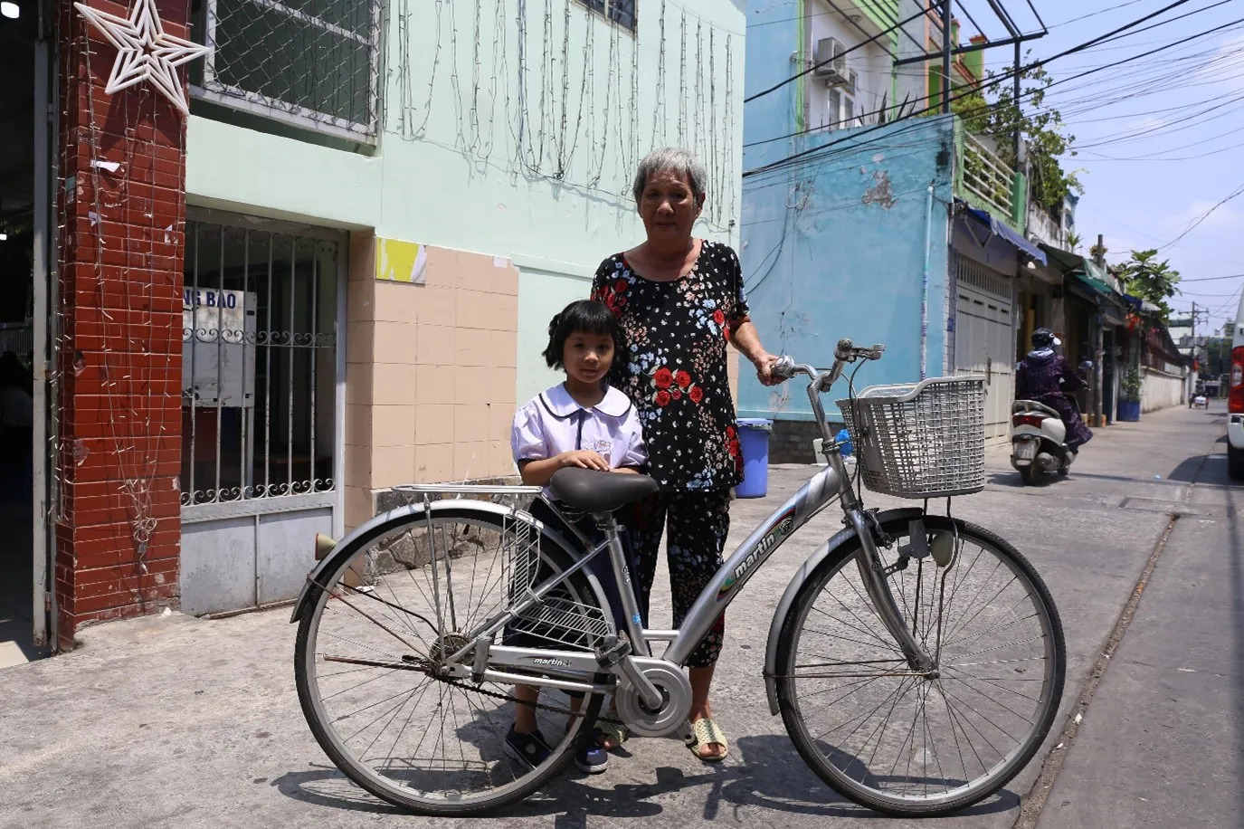 Ms Le Kim Duyen with her granddaughter and a bicycle gifted by the school so she could take her granddaughter to school. 