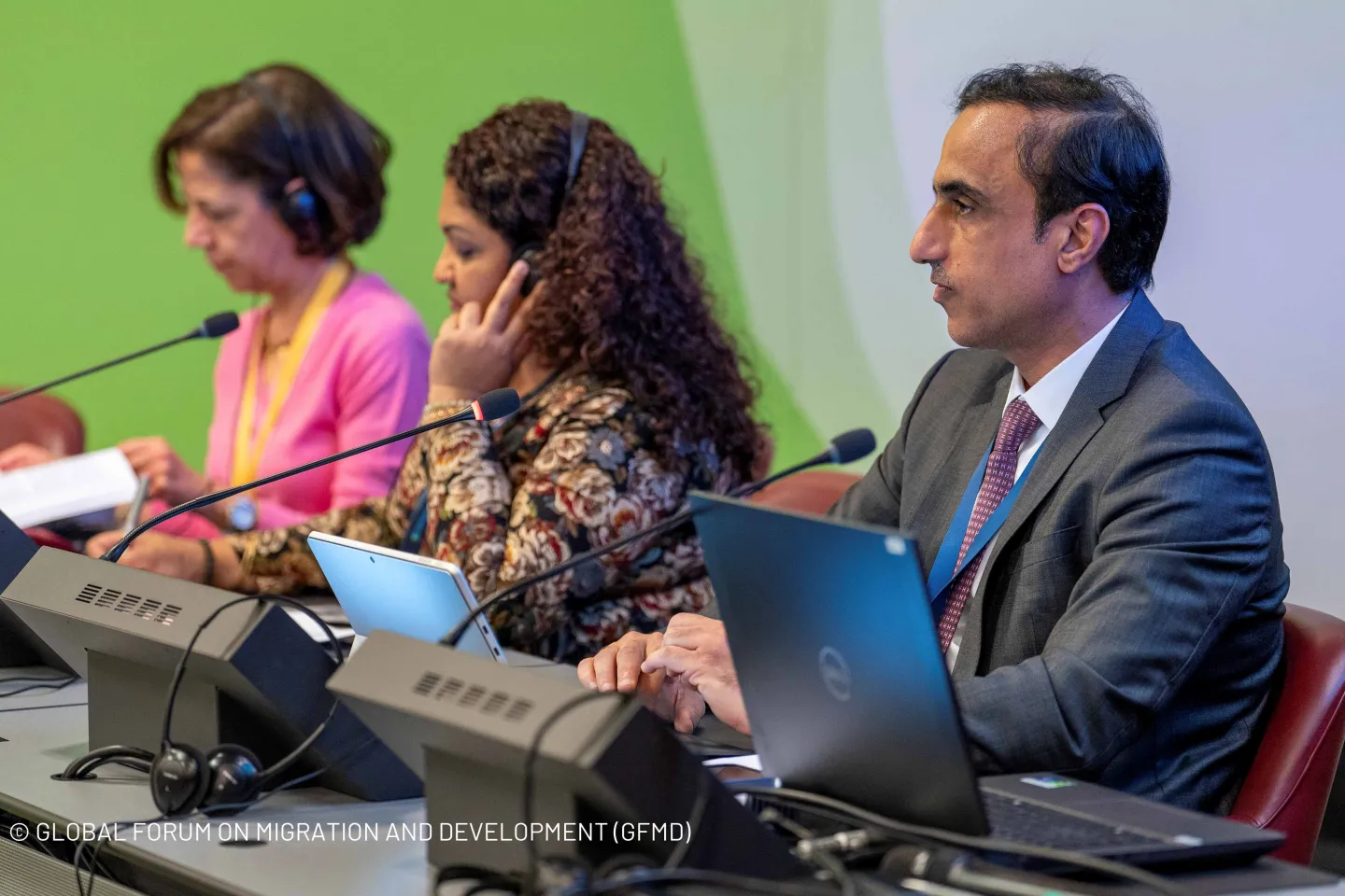 Three panelists, listening to debate on headphone with their laptops open