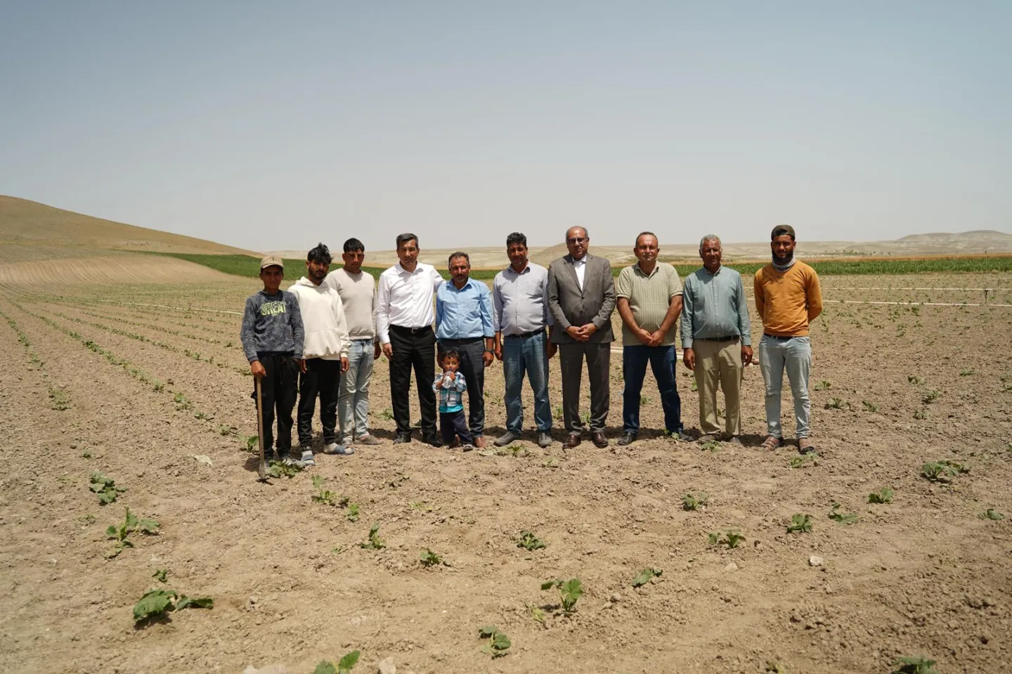 Bir kucuk cocuk, bir grup buyuk adam ile Polatli, Ankara'da bir tarlada.