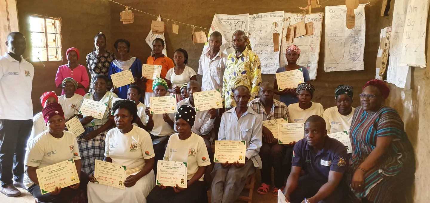 women in their community pose with their certificate commitment to fight child labour