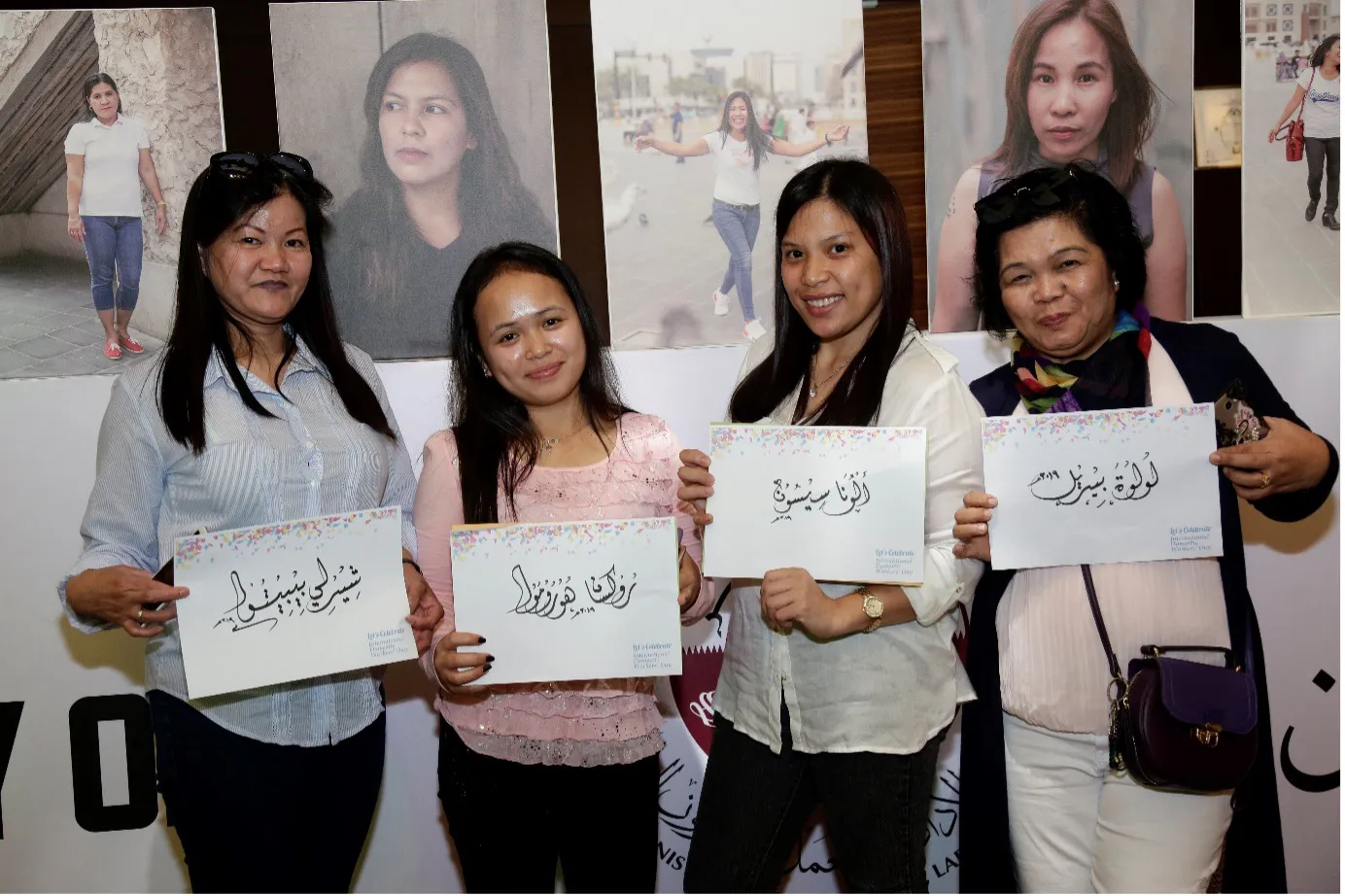 Four women holding signs in Arabic for Domestic Workers' Day celebration in Doha, Qatar