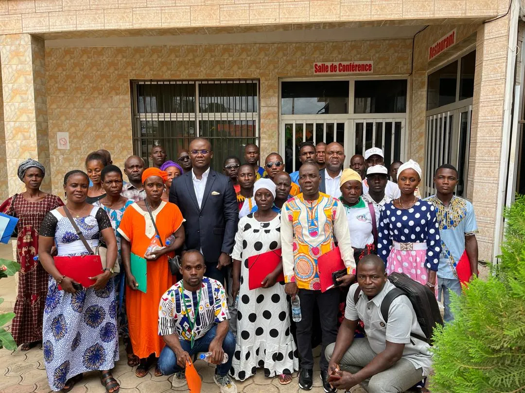 Participants dressed in traditional colourful clothes pose for a picture with folders in their hands
