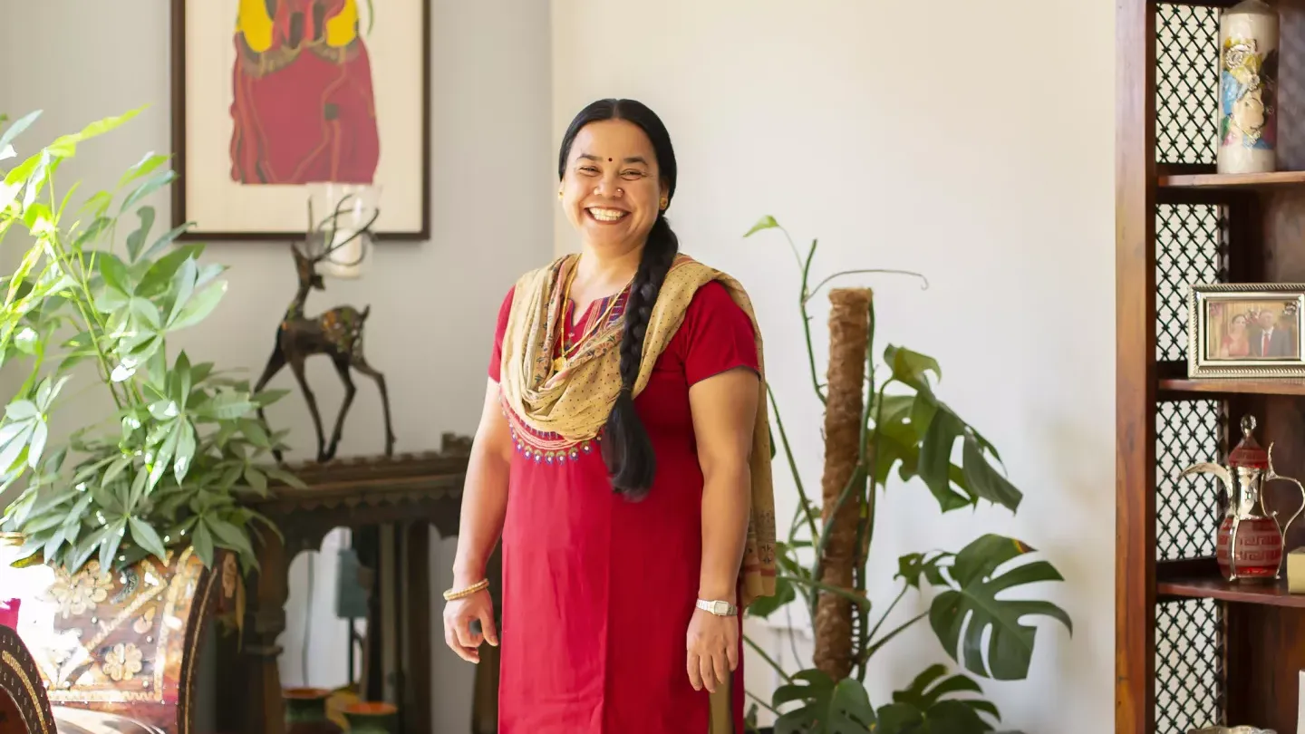 A Nepalese woman in traditional dress smiling in a house, in Qatar