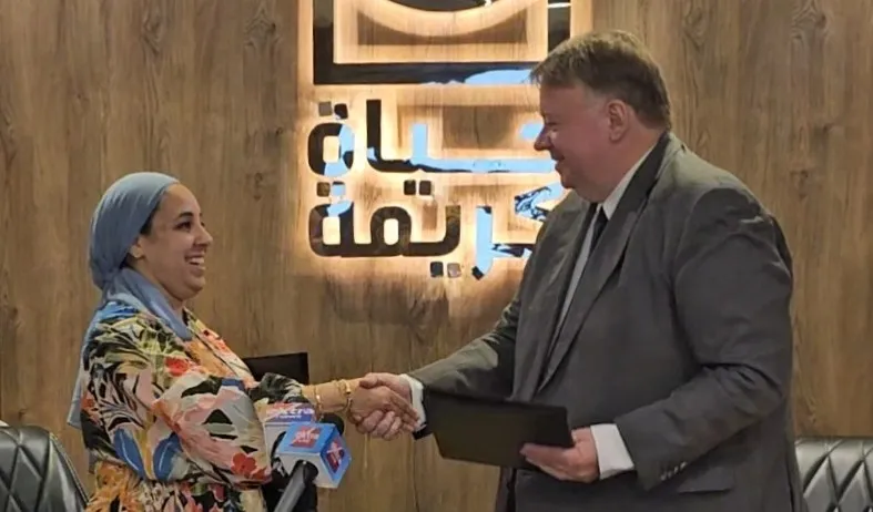 A man and a woman shake hands in a professional office setting, symbolizing collaboration and agreement.
