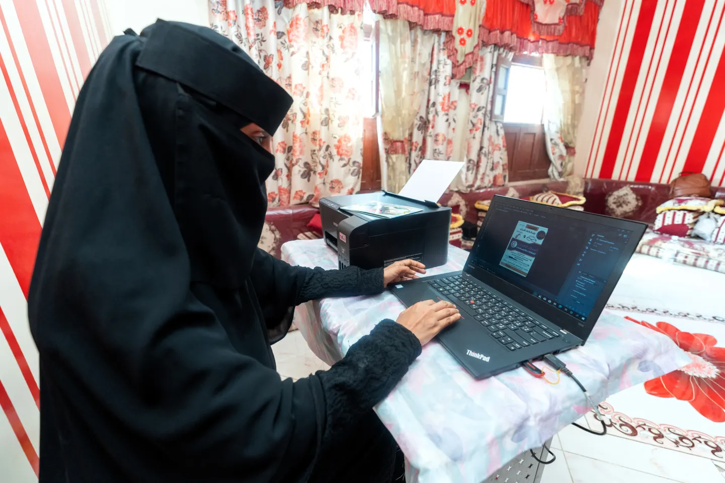 Aswan working on her laptop making designs for local businesses in her area after receiving grants and training through UNDP in Lahj Governorate.