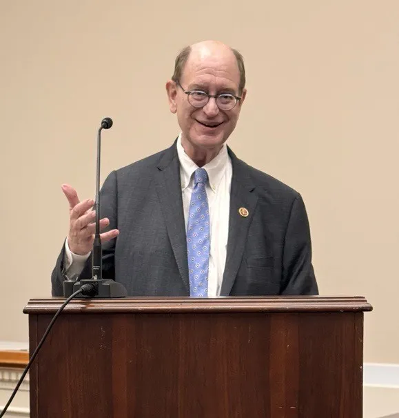 Man standing behind podium and raising his hand